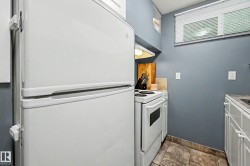 Compact kitchen featuring a full-sized refrigerator, white electric range with overhead lighting, white cabinetry, and a window with blinds - 