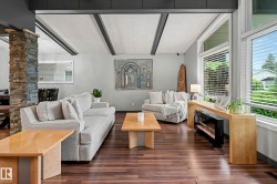 Spacious living area featuring wood-finish flooring, exposed ceiling beams, and a stone-clad structural pillar - 
