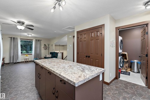 Kitchen island with a light-toned countertop, brown base cabinetry, and dark hardware - 5210 55 Avenue, Wetaskiwin, AB 