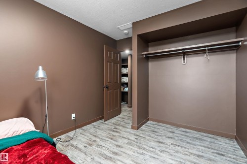 Room featuring wood-finish flooring, a built-in closet with hanging rod, and a six-panel interior door - 5210 55 Avenue, Wetaskiwin, AB 