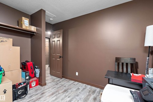Interior room with wood-finish flooring, warm brown wall tones, and a built-in closet system featuring an upper shelf and hanging rod - 5210 55 Avenue, Wetaskiwin, AB 