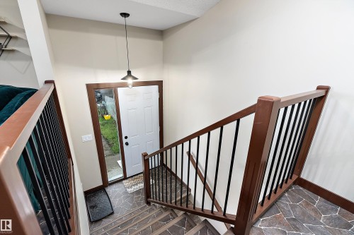 Foyer with stone-look tile flooring, white entry door with frosted sidelight, and an industrial-style pendant light fixture - 5210 55 Avenue, Wetaskiwin, AB 