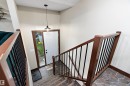 Foyer with stone-look tile flooring, white entry door with frosted sidelight, and an industrial-style pendant light fixture - 5210 55 Avenue, Wetaskiwin, AB 