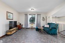 Spacious living area featuring unique flagstone-patterned flooring, a large window providing natural light, and a contemporary flush-mount ceiling light fixture - 5210 55 Avenue, Wetaskiwin, AB 