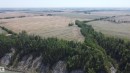Expansive land parcel featuring a dense forest bordering agricultural fields and a water body with rocky banks - 6015 200 Street, Edmonton, AB 