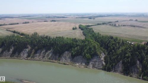 Riverfront property with mature treeline, sloped banks, and expansive open fields beyond - 6015 200 Street, Edmonton, AB 