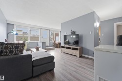 Spacious living area featuring light gray walls and wood-finish flooring - 