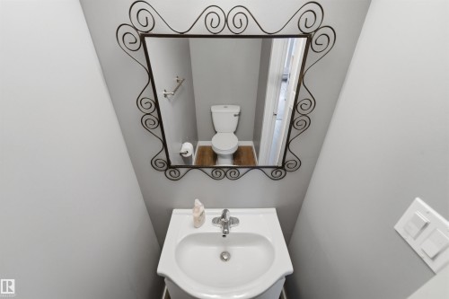 Pedestal sink with chrome faucet, complemented by a decorative iron-framed mirror - #110 7805 159 St Nw, Edmonton, AB 