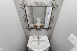 Pedestal sink with chrome faucet, complemented by a decorative iron-framed mirror - 