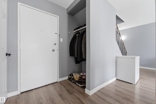 Entryway featuring wood-finish flooring, light gray wall paint, and white trim - #110 7805 159 St Nw, Edmonton, AB 