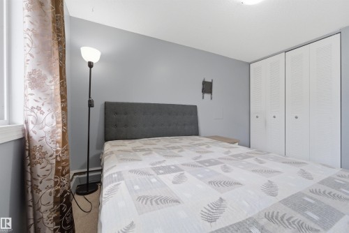 Bedroom featuring light grey walls, carpet flooring, and a window with white trim - #110 7805 159 St Nw, Edmonton, AB 