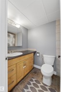Bathroom featuring a wood-finish vanity with an integrated sink, dark countertop, and tiled flooring - 