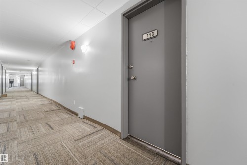 Entry door with number 110, featuring a matte gray finish and polished chrome hardware - #110 7805 159 St Nw, Edmonton, AB 