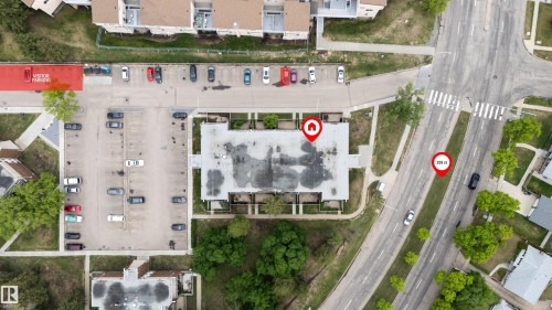Aerial view of a complex featuring multiple buildings, surface parking areas, and mature trees - #110 7805 159 St Nw, Edmonton, AB 