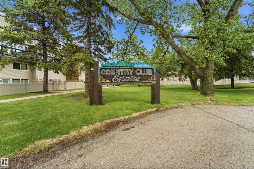 "Country Club Estates" entrance sign, set against a backdrop of mature trees and green lawns - #110 7805 159 St Nw, Edmonton, AB 