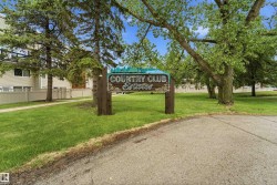 "Country Club Estates" entrance sign, set against a backdrop of mature trees and green lawns - 