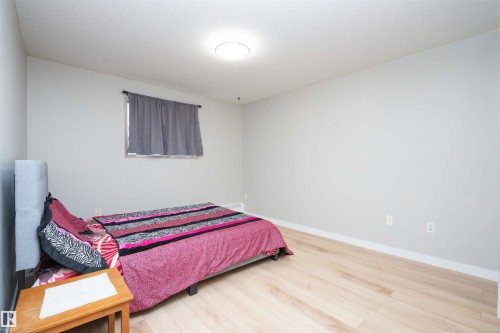 Bedroom featuring light wood-finish flooring, white baseboards, and a neutral wall color - 108 2508 50 Street, Edmonton, AB 