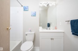 Bathroom with a white vanity featuring shaker-style cabinet doors and brushed nickel hardware - 