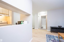 Pass-through kitchen opening to a room featuring light wood-finish flooring, light gray walls, and a recessed ceiling light - 