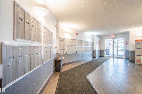 Lobby mailboxes with modern wall sconces, tile flooring, and a textured area rug - 108 2508 50 Street, Edmonton, AB 