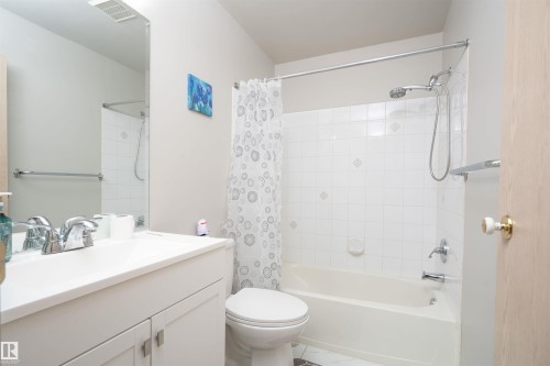 Bathroom featuring a full vanity with an integrated sink, chrome faucet, and a large mirror - 108 2508 50 Street, Edmonton, AB 
