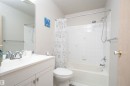 Bathroom featuring a full vanity with an integrated sink, chrome faucet, and a large mirror - 108 2508 50 Street, Edmonton, AB 