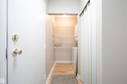 Entryway laundry area featuring wood-finish flooring, wire shelving, and a stackable washer and dryer unit - 