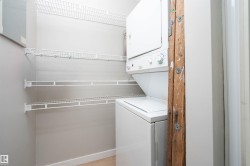 Dedicated laundry space featuring a stacked washer and dryer, multiple levels of white wire shelving, and light wood-finish flooring - 