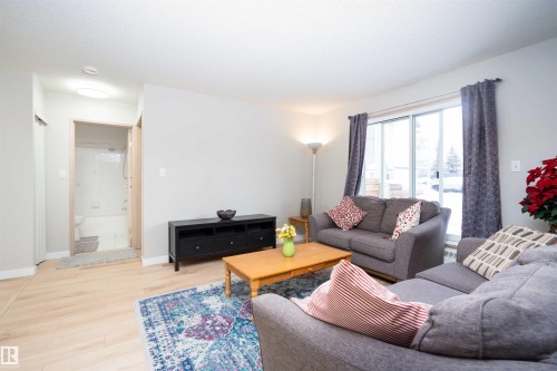 Bright living area featuring light wood-finish flooring and a sliding glass door - 108 2508 50 Street, Edmonton, AB 