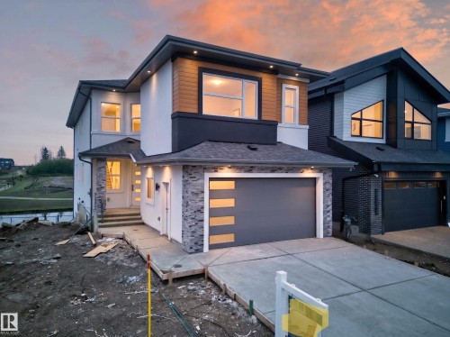 Modern exterior featuring white stucco, wood-finish siding, and stone veneer accents - 8737 Mayday Lane, Edmonton, AB 