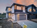 Modern exterior featuring white stucco, wood-finish siding, and stone veneer accents - 8737 Mayday Lane, Edmonton, AB 