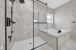 Spacious bathroom featuring a frameless glass shower enclosure with matte black fixtures and a rain showerhead - 