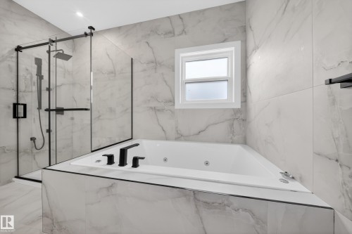 Sleek bathroom featuring a built-in soaking tub with matte black fixtures, a walk-in shower with a glass enclosure and black trim, and large format marble-look tile on the walls and floor - 8737 Mayday Lane, Edmonton, AB 
