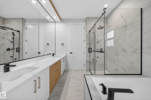 Contemporary bathroom featuring a dual vanity with white cabinetry, light wood-finish drawers, and matte black fixtures - 8737 Mayday Lane, Edmonton, AB 
