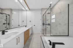 Contemporary bathroom featuring a dual vanity with white cabinetry, light wood-finish drawers, and matte black fixtures - 