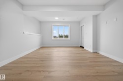 Spacious room featuring light wood-finish flooring, white walls, a large window, and recessed lighting - 