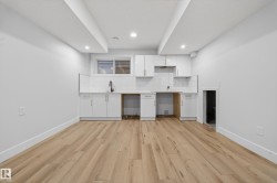 Contemporary kitchen area featuring wood-finish flooring, white cabinetry, a subway tile backsplash, recessed lighting, and a window with blinds - 