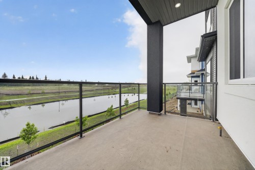 Balcony featuring concrete flooring, a modern glass and metal railing, and a dark soffit with recessed lighting - 8737 Mayday Lane, Edmonton, AB 