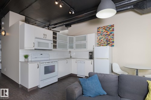 Kitchen area featuring white cabinetry, subway tile backsplash, and a full suite of white appliances - 411 10024 Jasper Avenue, Edmonton, AB 