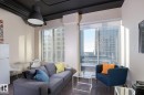 Floor-to-ceiling windows with roller shades, wood-finish flooring, and industrial-style exposed ceiling pipes - 411 10024 Jasper Avenue, Edmonton, AB 