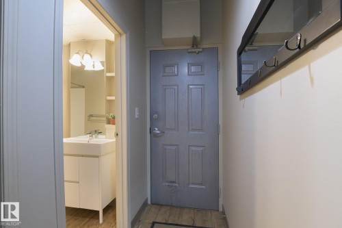 Entryway featuring wood-finish flooring and a wall-mounted coat rack with mirror - 412 10024 Jasper Avenue, Edmonton, AB 
