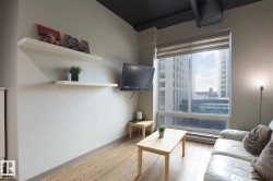 Living area featuring a large window with roller shades, wood-finish flooring, and a dark-painted ceiling - 