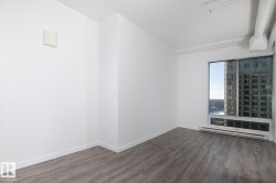 Expansive window with urban scenery, featuring wood-finish flooring, white baseboards, and a wall-mounted heating unit - 