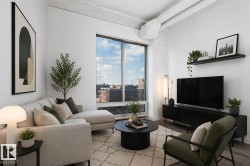 Bright living area featuring large windows, wood-finish flooring, white walls, exposed ceiling ducts, and a black floating shelf - 