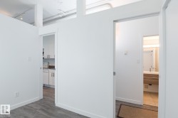 Bright interior space featuring wood-finish flooring, white walls, and exposed ceiling ductwork - 