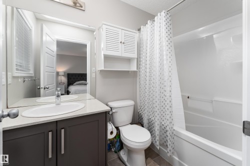 Full bathroom featuring a white tub/shower combination, dark gray vanity with a light countertop, and a wall-mounted storage cabinet - 9468 209 St, Edmonton, AB 