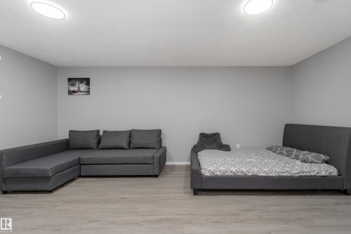 Spacious room featuring light wood-finish flooring, recessed lighting, and neutral gray walls - 9468 209 St, Edmonton, AB 