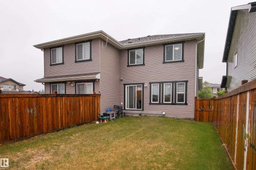Backyard featuring a privacy fence, green lawn, and multi-level house exterior - 9468 209 St, Edmonton, AB 