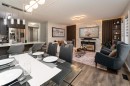 Open-concept living area featuring wood-finish flooring, a contemporary dining chandelier, and a kitchen island with pendant lighting - 9468 209 St, Edmonton, AB 
