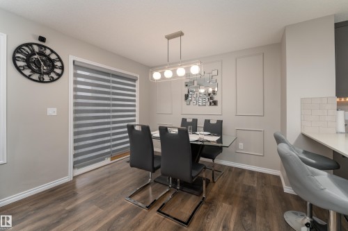 Dining area featuring wood-finish flooring and a contemporary linear chandelier - 9468 209 St, Edmonton, AB 